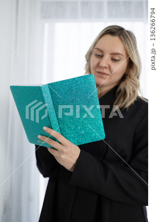 Smiling Woman Wearing Black Suit Reading a Book Indoors During Daytime Smiling Woman Wearing Black Suit Reading a Book Indoors During Daytime 136266794