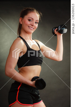 Fit woman exercising with dumbbells. 136266913