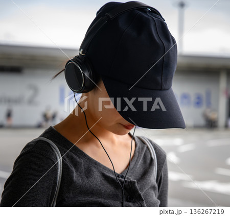 空港で音楽を聴く女性 ■撮影協力：関西国際空港（KIX） 136267219