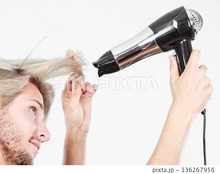 Young man drying hair with hairdryer 136267958