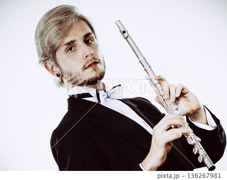 Male flutist wearing tailcoat holds flute 136267981