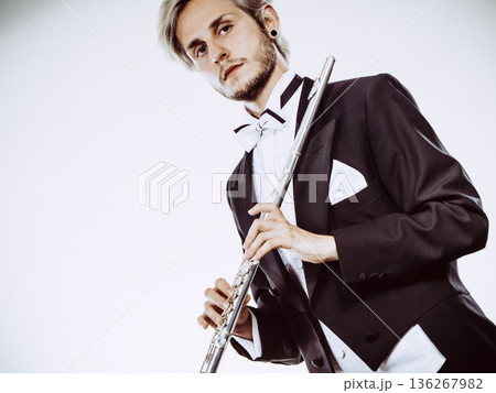 Male flutist wearing tailcoat holds flute 136267982