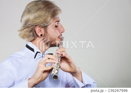 Male flutist playing his flute 136267996