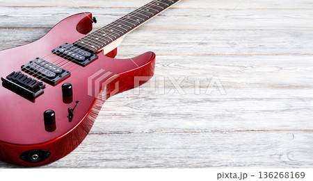 Red electric guitar resting on white wooden background 136268169