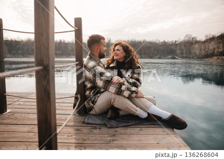 Couple sitting on a dock by the lake enjoying a day together near water during a romantic outing in winter 136268604