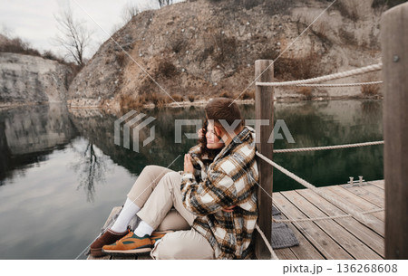 Couple enjoying a quiet moment by the water on Valentines Day while wrapped in a cozy blanket at the lake Couple enjoying a quiet moment by the water on Valentines Day while wrapped in a cozy blanket at the lake 136268608