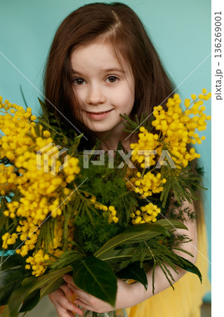 Girl with yellow mimosa bouquet on turquoise background 136269001