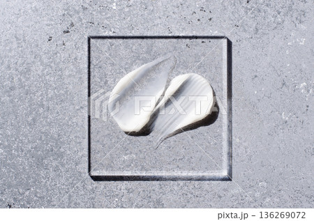 A sample of white body cosmetics on a glass square. Grey background. 136269072