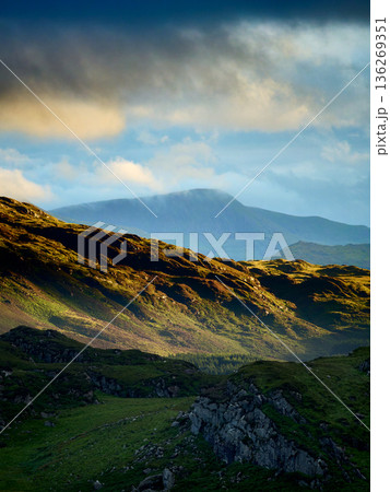 Hills and valleys meet the cloudy horizon. 136269351