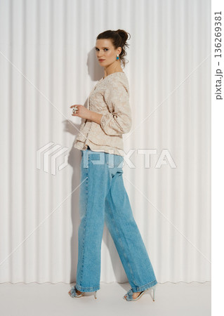 Model poses in casual outfit against white backdrop during photoshoot in urban studio setting Model poses in casual outfit against white backdrop during photoshoot in urban studio setting 136269381
