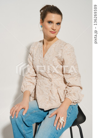 Woman in light-colored blouse and blue jeans poses for a photo in a studio setting Woman in light-colored blouse and blue jeans poses for a photo in a studio setting 136269389