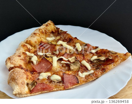 A close-up shot of a large classic pizza with cheese, ham, and mushrooms. A delicious, nutritious, and quick meal. 136269458