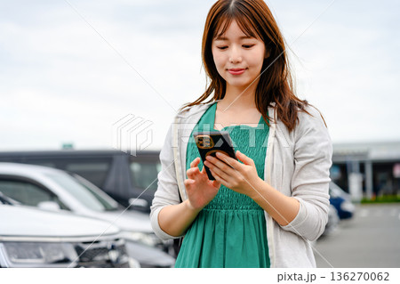 駐車場でスマホ操作する女性 ■撮影協力:関西国際空港(KIX) 駐車場でスマホ操作する女性 ■撮影協力:関西国際空港(KIX) 136270062