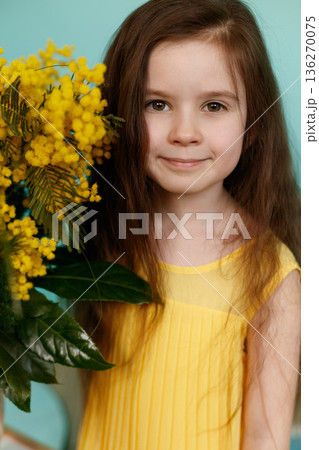 Girl with yellow mimosa bouquet on turquoise background 136270075