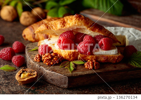 Croissant with camembert cheese, raspberries and walnuts. 136270134