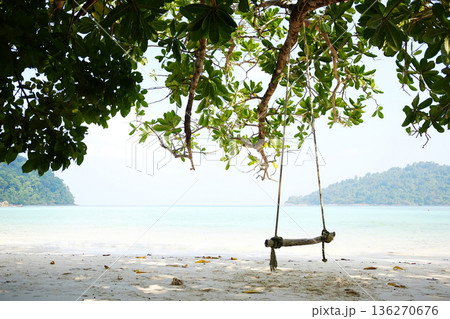 Beautiful view for Relaxation with wooden swing hanging on green big tree over beach sea on summer in Thailand Beautiful view for Relaxation with wooden swing hanging on green big tree over beach sea on summer in Thailand 136270676