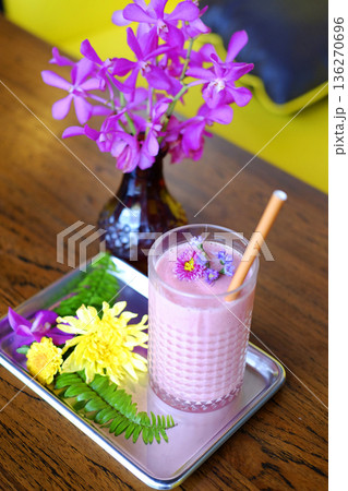 Top view of a glass of blueberries smoothie and violet flowers decorated on topping 136270696