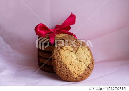 Round oatmeal cookies with a heart, tied with a red ribbon bow on a pink background of crumpled paper. A festive concept for Valentine's Day, March 8 and Christmas 136270715