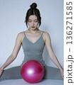 Woman is sitting on the floor with a pink ball in her lap 136271585