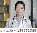 Woman in a white lab coat is smiling for the camera 136271586