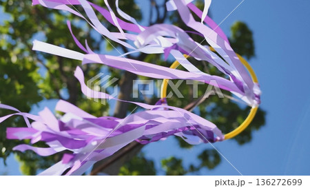 Purple ribbons dancing in wind at outdoor celebration against blue sky 136272699