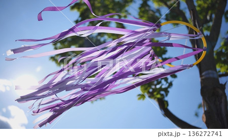 Purple and white ribbons flowing in wind against blue sky and bright sun Purple and white ribbons flowing in wind against blue sky and bright sun 136272741