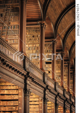 Old library interior with ornate wooden architecture and endless bookshelves 136274074