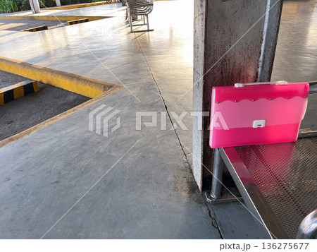 forgotten pink document folder on metal bench at empty bus terminal or transit station forgotten pink document folder on metal bench at empty bus terminal or transit station 136275677