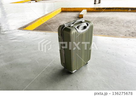 forgotten olive green hard shell suitcase on empty concrete terminal floor forgotten olive green hard shell suitcase on empty concrete terminal floor 136275678