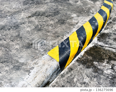 yellow and black striped concrete safety curb on sharp road curve for traffic warning yellow and black striped concrete safety curb on sharp road curve for traffic warning 136275696