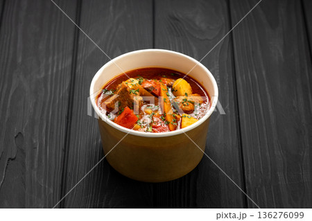 Hungarian bograch goulash soup with beef and vegetables in kraft bowl on dark wooden table Hungarian bograch goulash soup with beef and vegetables in kraft bowl on dark wooden table 136276099