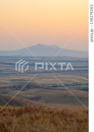 Scenic mountain sunset, golden hour over rolling plains, vibrant orange sky and peaceful natural landscape 136276263