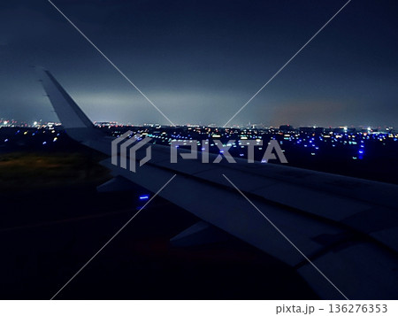 夜の飛行場の滑走路を進む飛行機の翼と夜景 夜の飛行場の滑走路を進む飛行機の翼と夜景 136276353