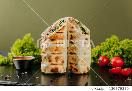 Grilled tuna tortilla wraps with greens, sauce and tomatoes on slate 136276359