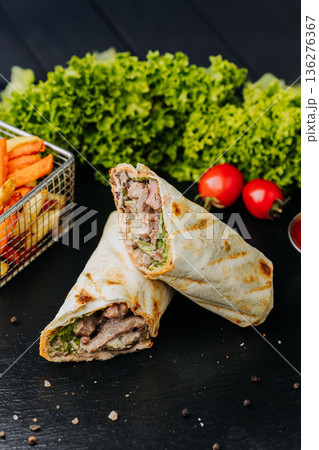Pork shawarma wraps with fries and ketchup sauce on black table, close up 136276367