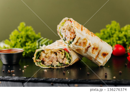 Grilled chicken tortilla wraps with greens and sauce on black slate Grilled chicken tortilla wraps with greens and sauce on black slate 136276374