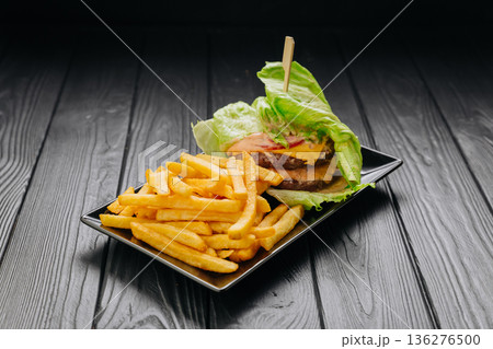 Bunless beef burger in lettuce wrap with fries on black plate, copy space Bunless beef burger in lettuce wrap with fries on black plate, copy space 136276500