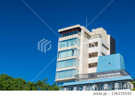 Window cleaner man cleansing on high building against blue sky, Fukuoka Window cleaner man cleansing on high building against blue sky, Fukuoka 136276583