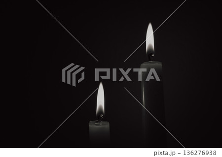 Two burning candles in black and white style, mourning concept or energy blackout background, symbol of memory and light during darkness 136276938