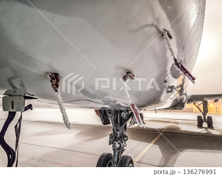 icy aircraft on a winter tarmac. Frozen Remove Before Flight tags and landing gear in freezing weather. icy aircraft on a winter tarmac. Frozen Remove Before Flight tags and landing gear in freezing weather. 136276991