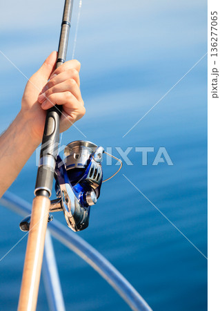 Man holding fishing rod, blue in background Man holding fishing rod, blue in background 136277065