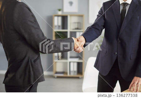 Two business professionals shaking hands in office after successful meeting and making agreement. 136277338