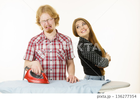 Happy woman and bored man ironing clothes 136277354