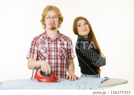 Happy woman and bored man ironing clothes 136277355