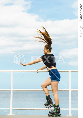 Girl wearing roller skates on seaside Girl wearing roller skates on seaside 136277392