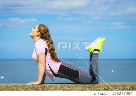 Woman doing yoga next to sea 136277394