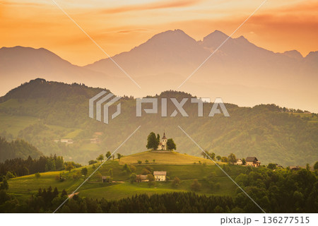 Sveti Tomaz, Slovenia. Hilltop church framed by panoramic countryside landscape under dramatic skies Sveti Tomaz, Slovenia. Hilltop church framed by panoramic countryside landscape under dramatic skies 136277515