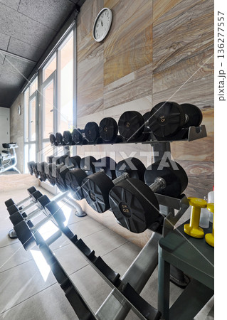 Racked dumbbells organized on stands Racked dumbbells organized on stands 136277557