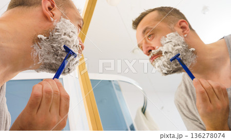 Guy shaving his beard in bathroom Guy shaving his beard in bathroom 136278074
