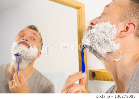 Guy shaving his beard in bathroom Guy shaving his beard in bathroom 136278085